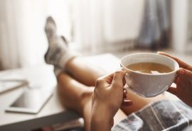 Uma mulher tomando uma xícara de chá para aliviar a sensação de frio dolorido.
